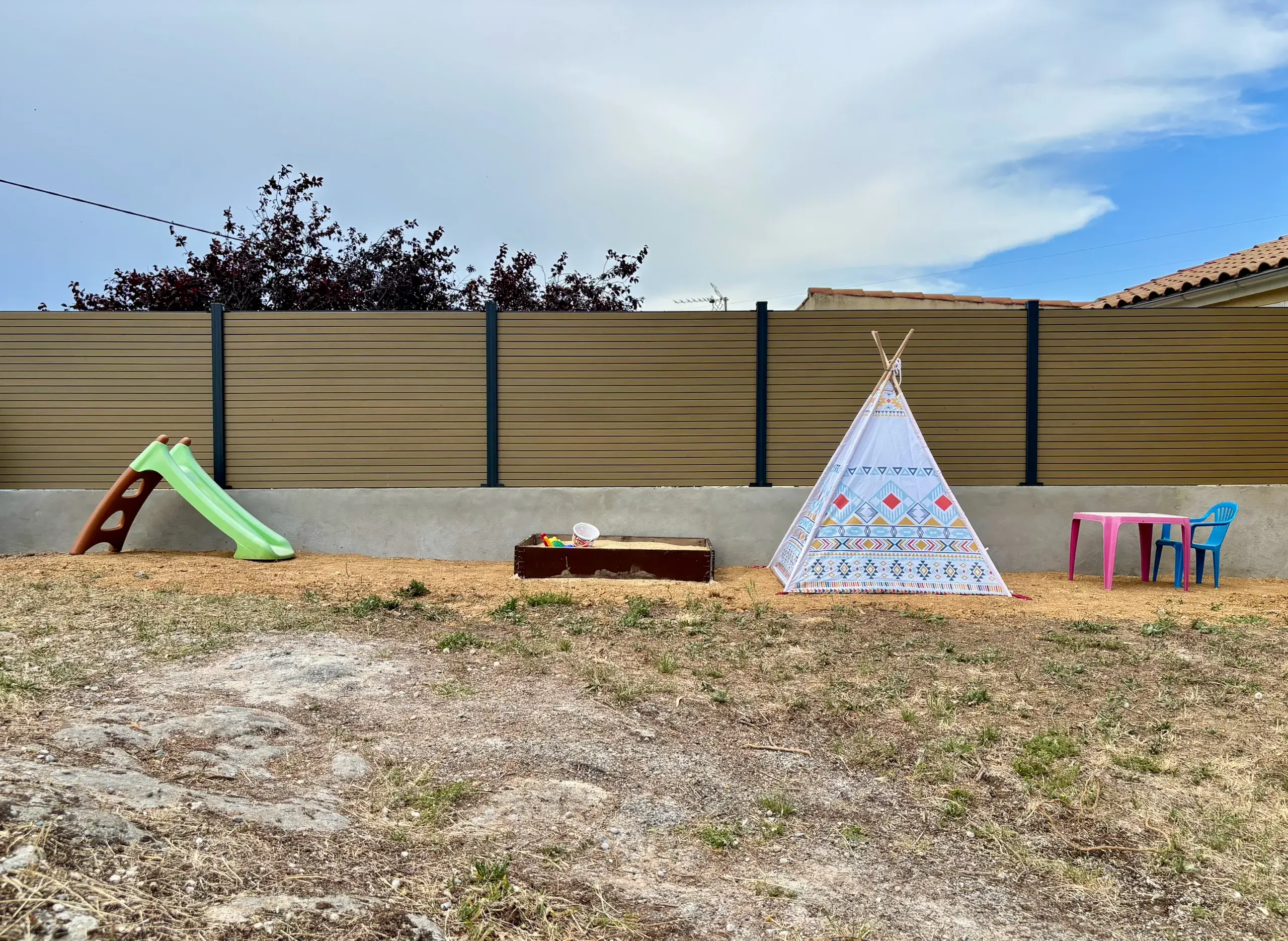 Espace de jeux pour enfants avec toboggan, bac à sable et tipi